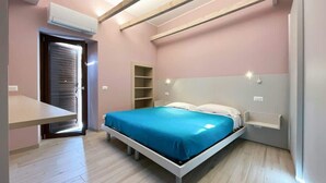 A bedroom with a bed, a bedside table, a built-in shelf, and a door.