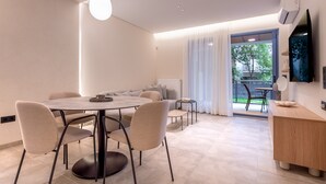 A modern dining area with a round table and chairs, a sofa, and a small side table. -  Phaedrus Living Athens Luxury Residences Ivory (Athens)
