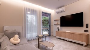 A modern living room with a sofa, a small table, a TV mounted on the wall, and a sliding glass door leading to an outdoor area. -  Phaedrus Living Athens Luxury Residences Ivory (Athens)