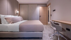 A modern bedroom with a bed, bedside table, and chair. -  Phaedrus Living Athens Luxury Residences Ivory (Athens)