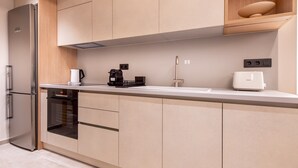 A modern kitchen with a built-in oven, a coffee maker, and a white toaster on the counter. -  Phaedrus Living Athens Luxury Residences Ivory (Athens)