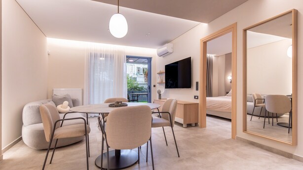 A modern hotel room with a dining area, a sofa, a bed, a TV, and a large mirror. -  Phaedrus Living Athens Luxury Residences Ivory (Athens)