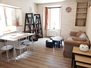 A living room with a wooden floor, a dining table with chairs, a sofa, a coffee table, and a small side table with a decorative item. - Ground floor, tv, 31m², Villard de Lans (Villard-de-Lans)