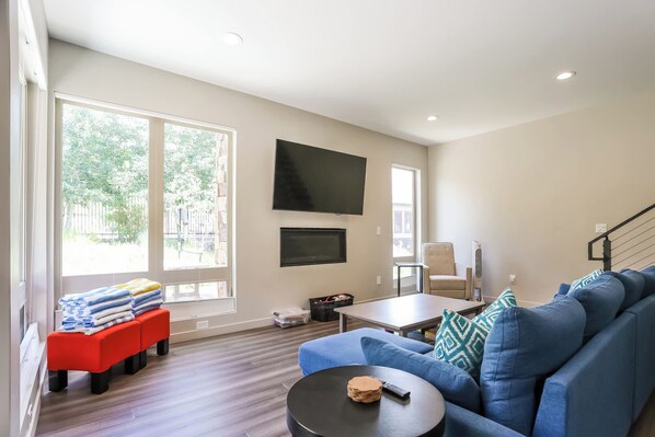 A modern living room with a blue sofa, a small round table, and a red bench with towels.