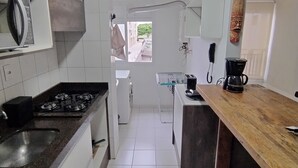A modern kitchen with white cabinets, a gas stove, a microwave, a coffee maker, and a view of the outside through a window.