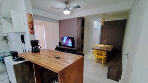 A compact living space with a wooden dining table, a TV, and a ceiling fan.