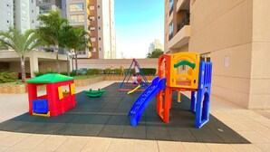 A playground with a small red and yellow playhouse, a blue slide, and a climbing structure.