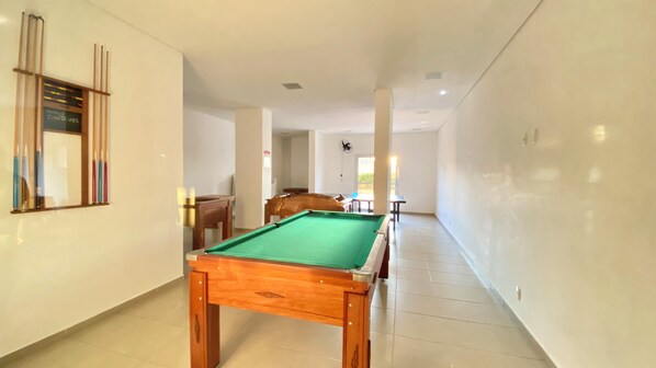 A hallway with a pool table, wooden furniture, and a fan.