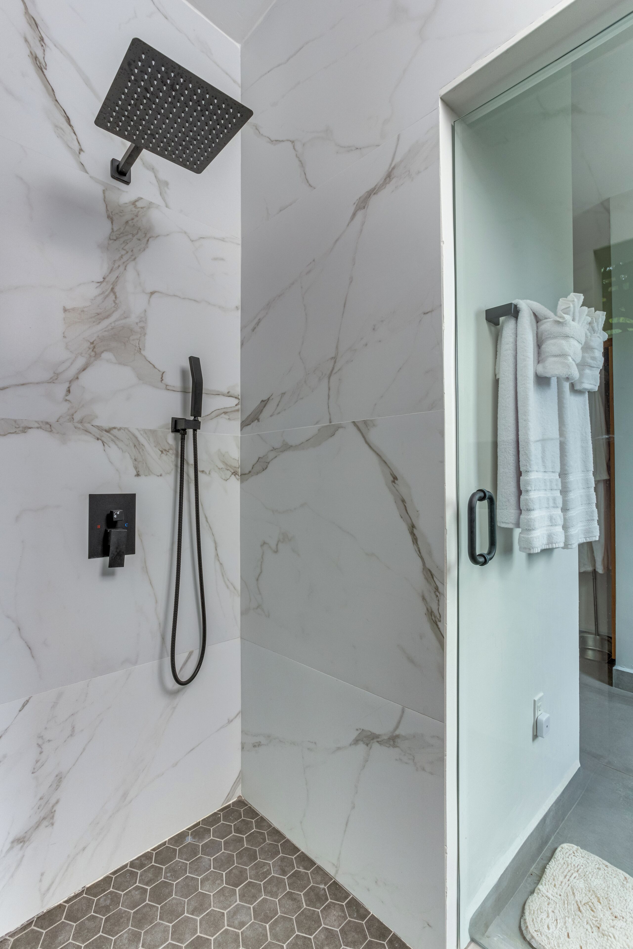 A modern bathroom with a shower, a glass door, and a tiled floor.