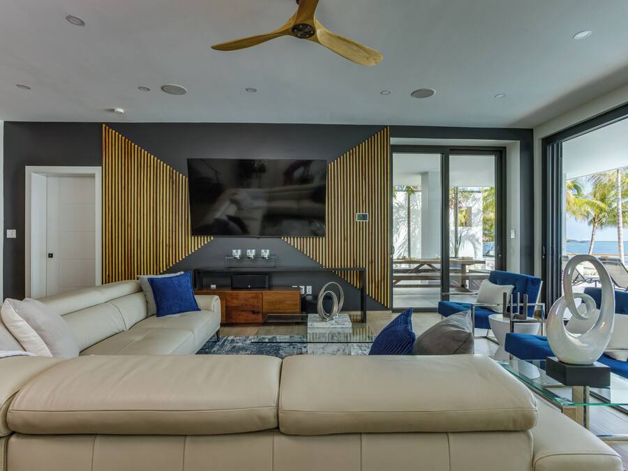 A modern living room with a large beige sectional sofa, a glass coffee table, and a ceiling fan.