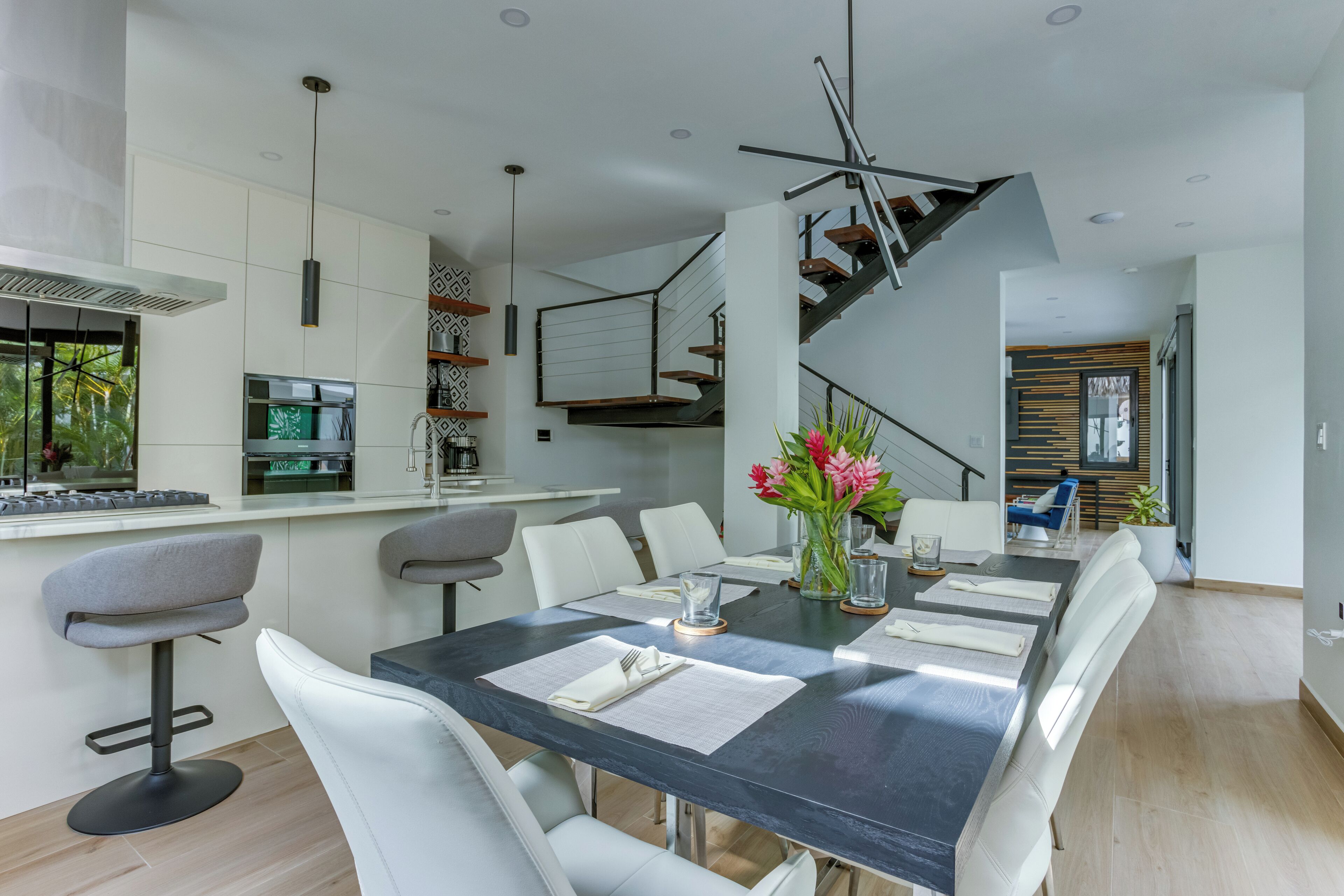 A modern dining area with a dark table, white chairs, and a vase with flowers.