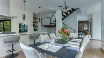 A modern dining area with a dark table, white chairs, and a vase with flowers.