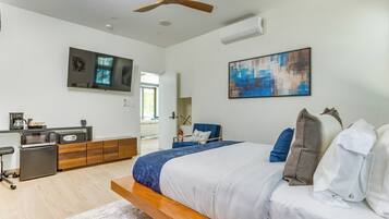 A modern bedroom with a bed, a desk, a chair, and a television.