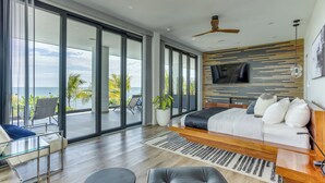 Un dormitorio moderno con una cama grande, televisión y vista al océano.