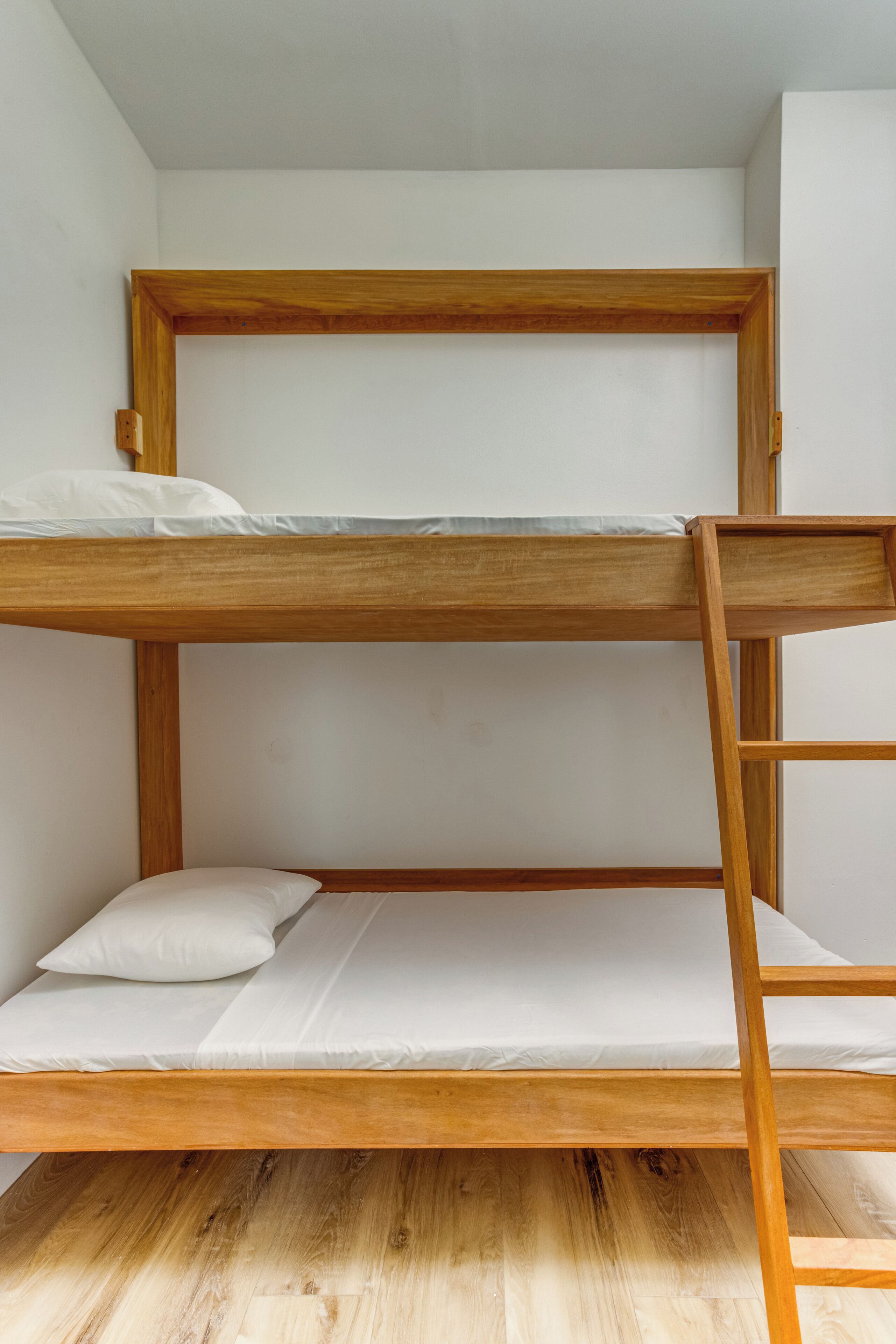 A bunk bed with a wooden frame and white bedding.