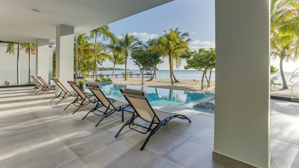 Zona junto a la piscina con sillones de descanso y vistas a la playa y al océano.
