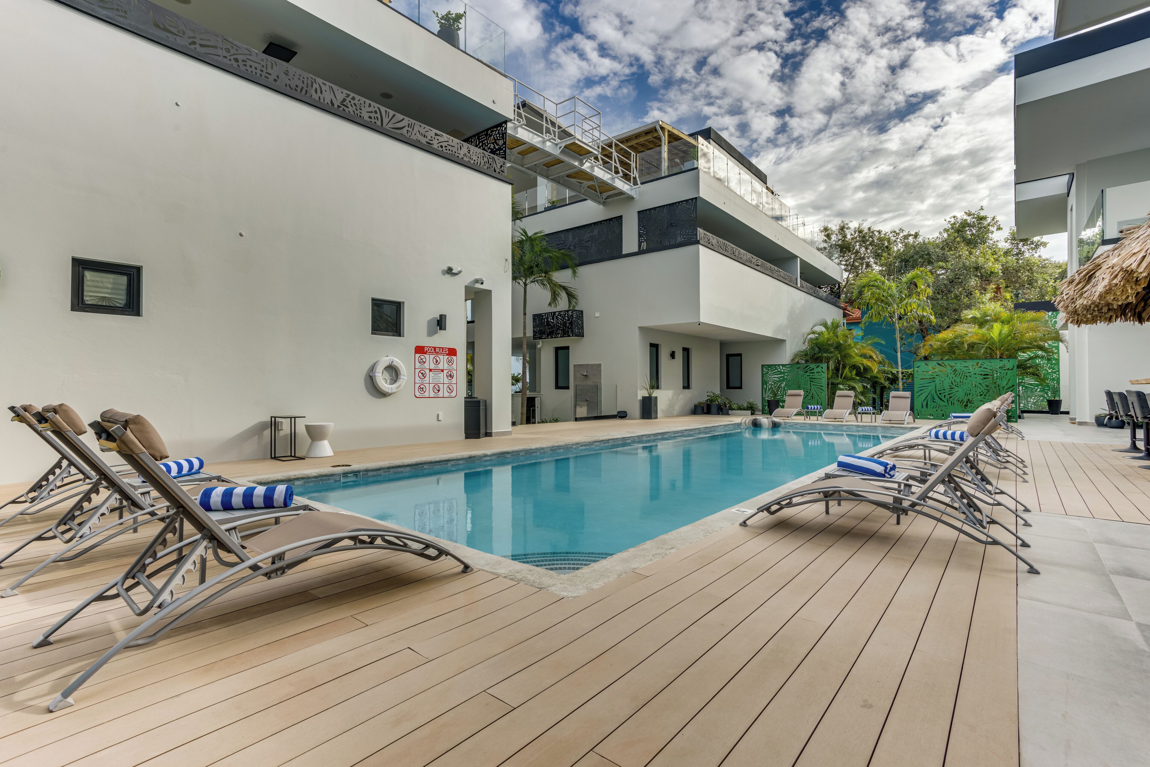 A modern outdoor swimming pool with sun loungers and a wooden deck.