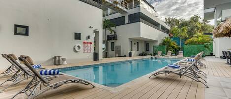 A modern outdoor swimming pool with sun loungers and a wooden deck.