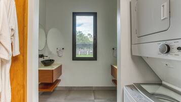 Pequeña lavandería con lavadora, un lavabo y una ventana con vistas al exterior.