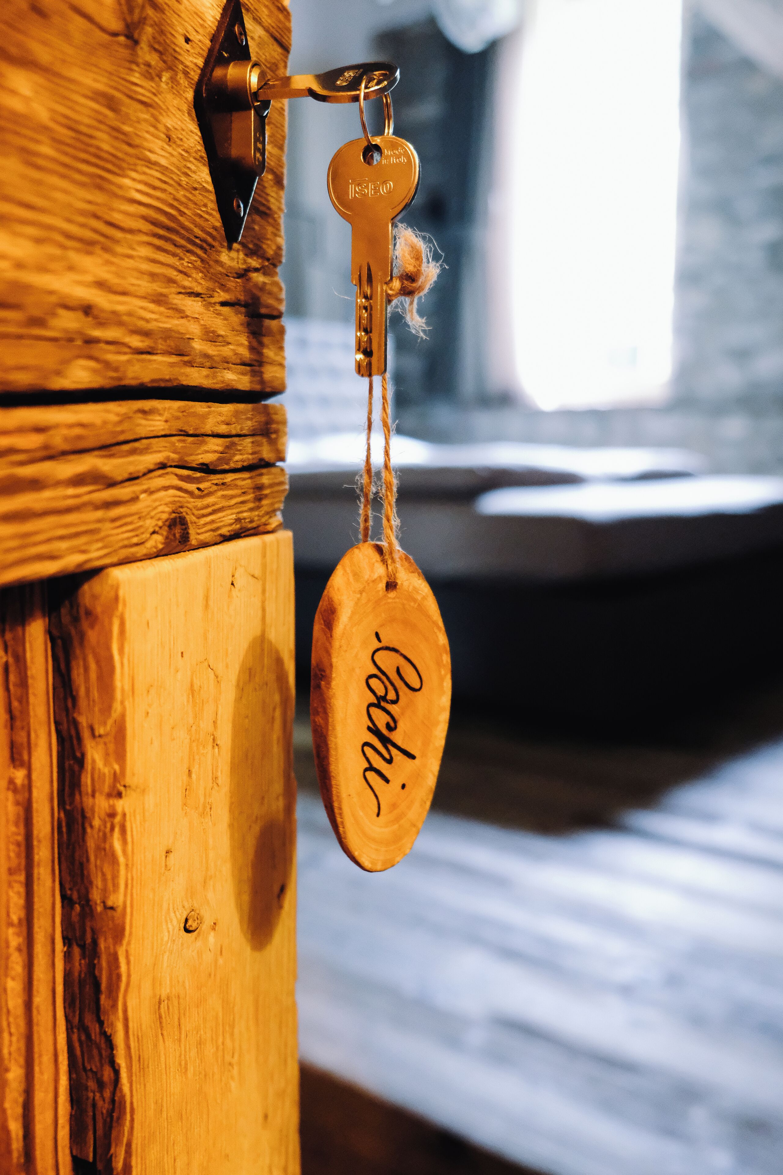A wooden door with a keyhole and a keychain with a name tag.
