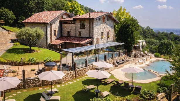 Una casa de pedra amb piscina, zona d'estar a l'exterior i vistes al paisatge circumdant.
