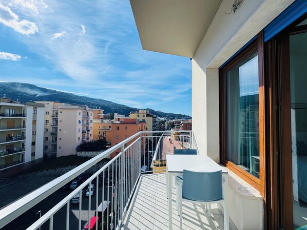 A balcony with a table and chairs, overlooking a street with parked cars and buildings in the background. - Vera Gioia Rooms de Charme (Sorrento)