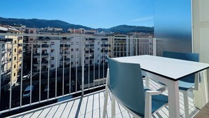 A balcony with a table and chairs, overlooking a residential area with multiple buildings and a mountain in the background. - Vera Gioia Rooms de Charme (Sorrento)