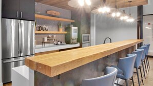 Une cuisine moderne avec un comptoir-bar en bois, des appareils en acier inoxydable et des chaises bleues.