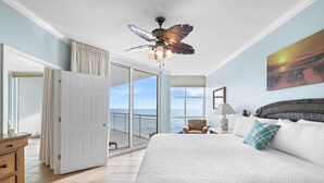 A bedroom with a large bed, a ceiling fan, a view of the ocean, and a balcony. - Palacio 303 (Pensacola)
