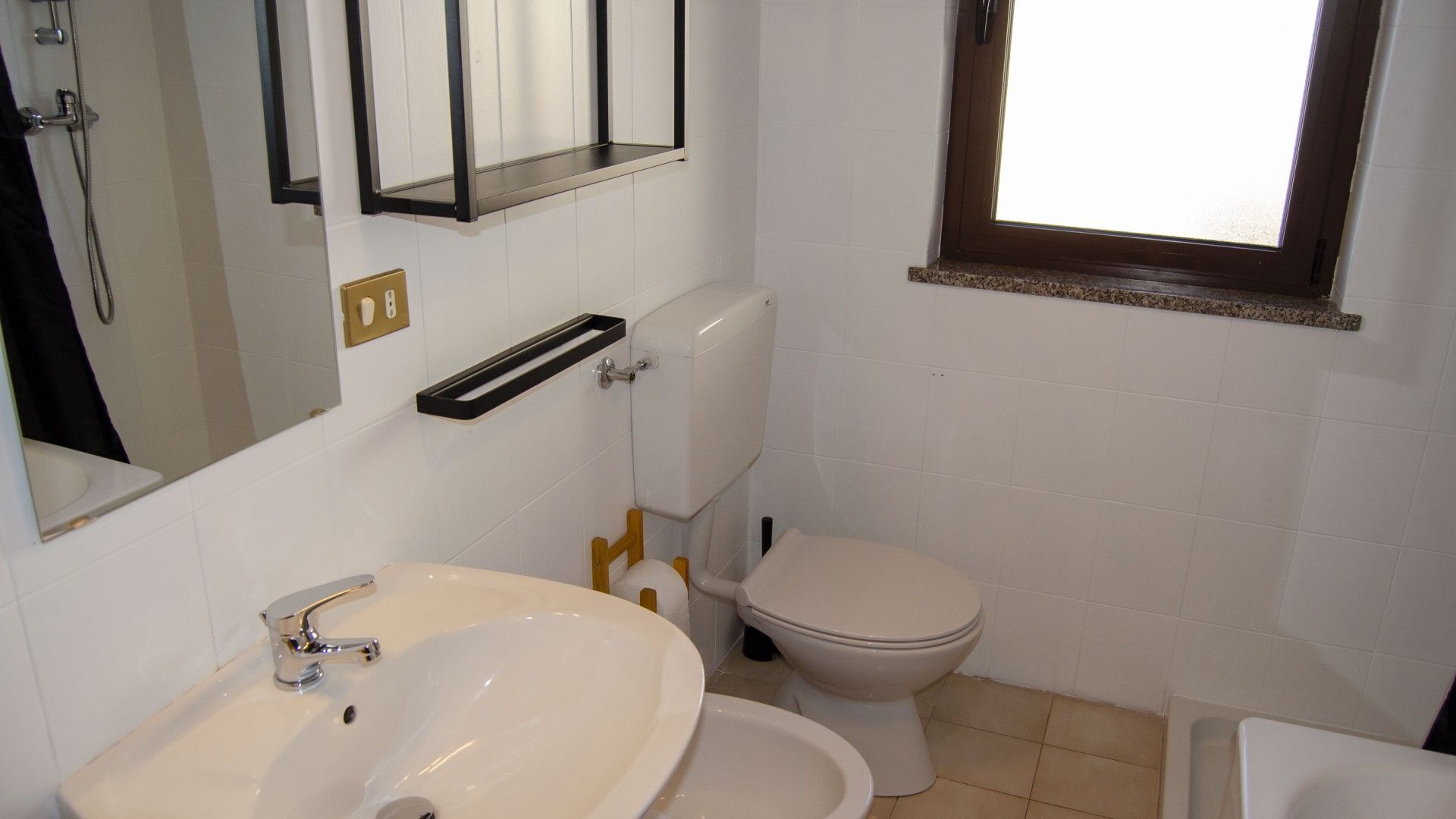 A bathroom with a white sink, toilet, and a window.