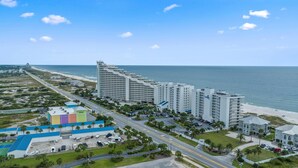 Un hôtel situé sur la côte, composé de plusieurs immeubles de grande hauteur, avec une plage et une route menant à la plage.