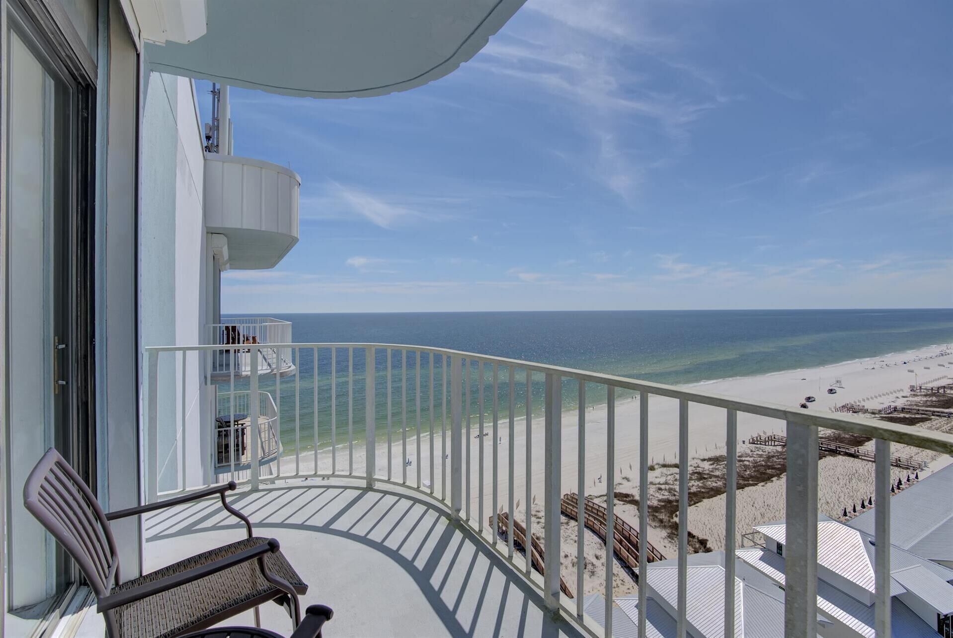 A balcony with a view of the beach and ocean.