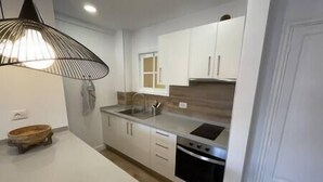 A modern kitchen with white cabinets, a stainless steel sink, and a built-in oven. - Alcalá on the beach with stunning views of Teide (Alcalá)