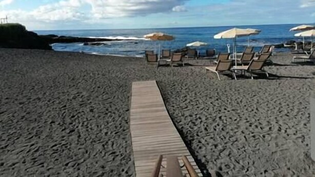 A beach with a wooden walkway leading to lounge chairs and umbrellas. - Alcalá on the beach with stunning views of Teide (Alcalá)