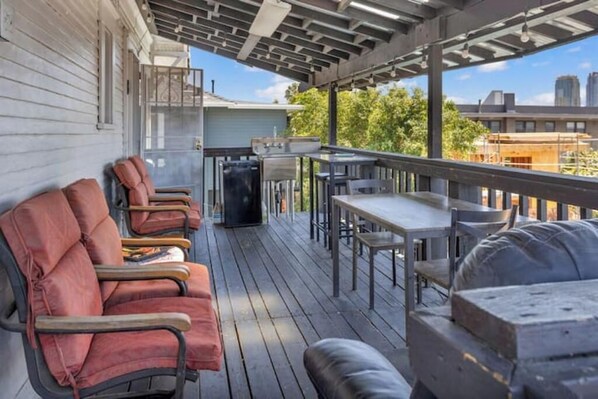 Eine überdachte Terrasse mit Sitzgelegenheiten und Grill.