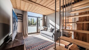 Ein modernes Wohnzimmer mit Holzboden, einem grauen Sofa, einem gemusterten Teppich und einer Treppe mit Holzhandläufen.