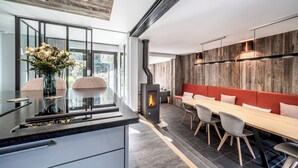 Eine moderne Küche mit einer zentralen Kochinsel, einem Essbereich mit langem Tisch und Stühlen sowie einer holzverkleideten Wand.