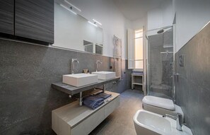 A modern bathroom with a large mirror, two sinks, a shower, and a toilet. - Rocco's Home at the Colosseum (Roma)
