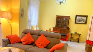 A living room with a sofa, a dining table, chairs, a cabinet, a lamp, and a wicker basket. - Rocco's Home at the Colosseum (Roma)