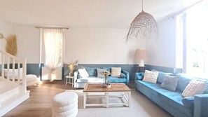 A living room with a blue sofa set, a wooden coffee table, and a hanging light fixture.