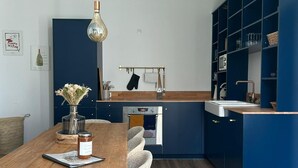 Une cuisine moderne avec une table à manger en bois, des chaises et des meubles de rangement bleus.