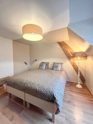 A bedroom with a bed, a lamp, and a sloped ceiling.