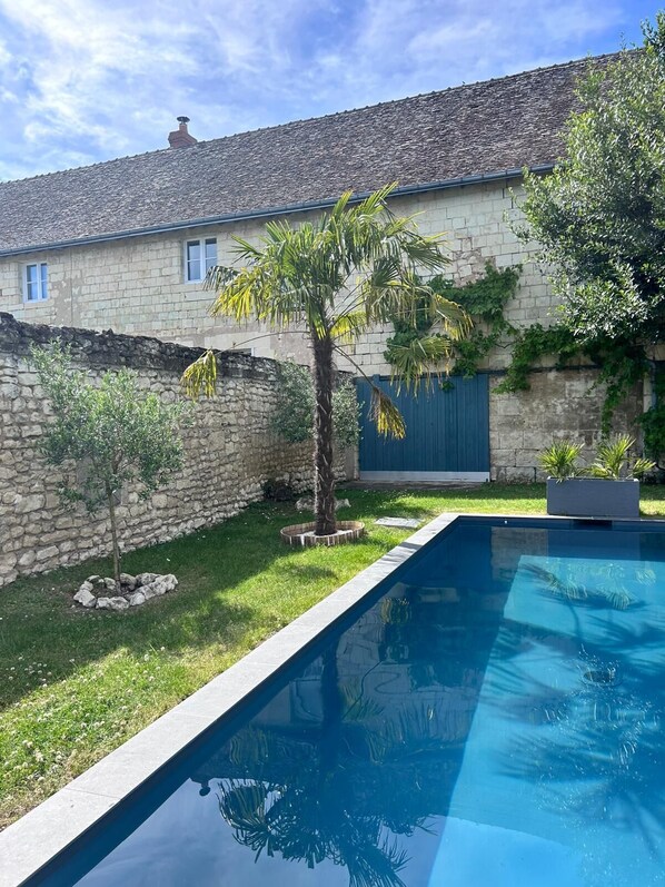 A swimming pool with a stone wall and a palm tree in the foreground. - South Touraine village house with swimming pool near Chinon Azay 10 p (Tavant)