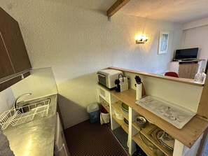 Une cuisine de taille réduite, équipée d’un évier, d’un four à micro-ondes et d’un plan de travail en bois.