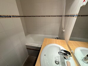 Une salle de bain avec une baignoire, un meuble-lavabo en bois et un miroir.