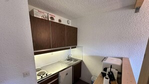 A compact kitchenette with a small refrigerator, a sink, and a countertop.