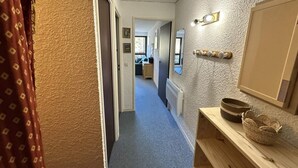 A narrow hallway with a wooden bench on the right, a radiator, and a mirror on the wall.