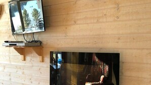 A wooden-paneled wall with a mounted television and a wall clock.