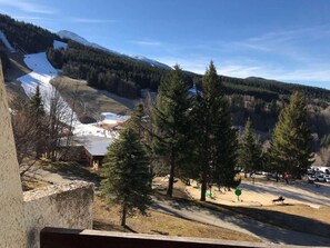A mountainous landscape with a ski lift, trees, and a building in the background.