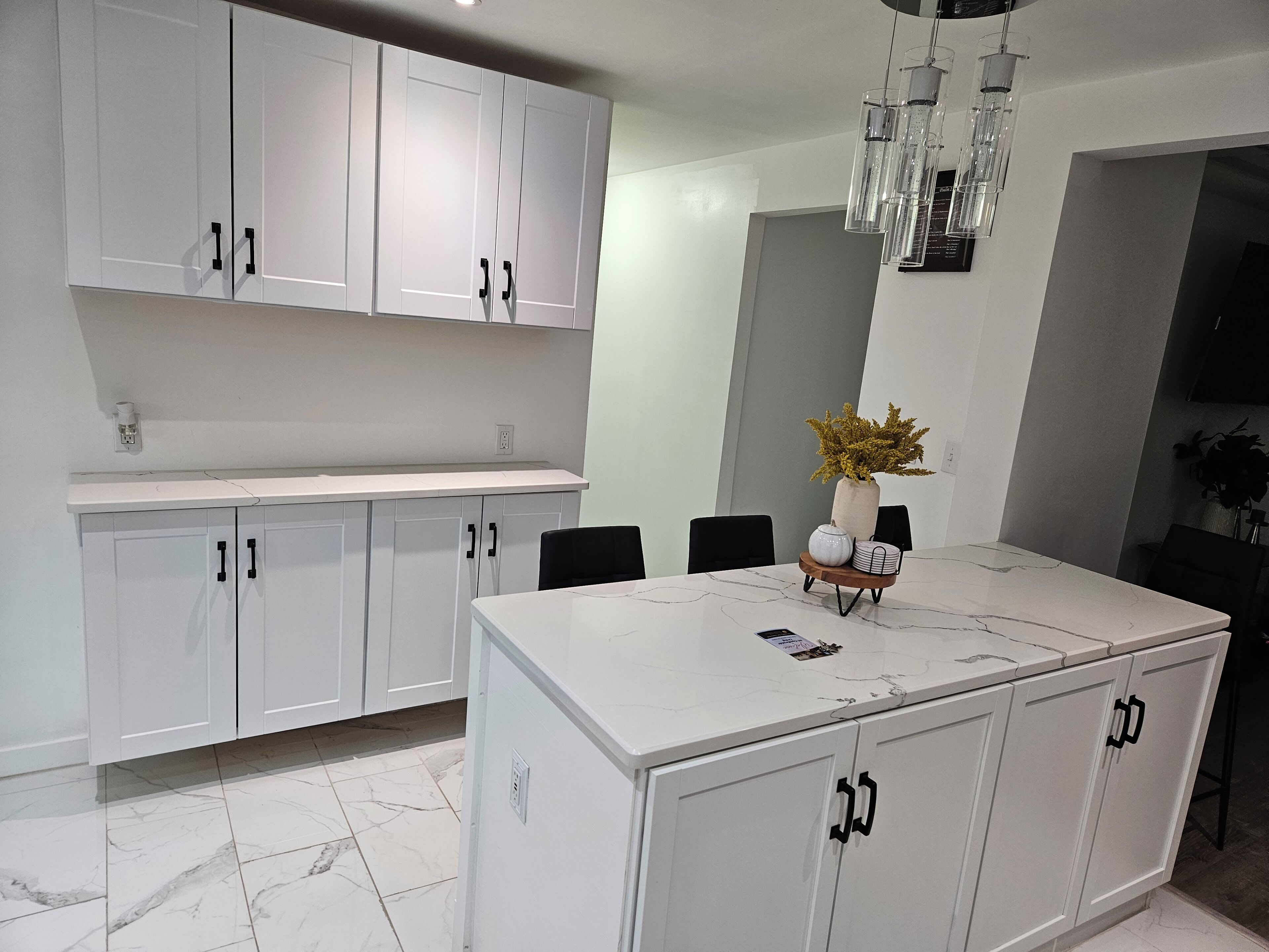 Een moderne keuken met witte kasten, een marmeren aanrecht en een centraal eiland.
